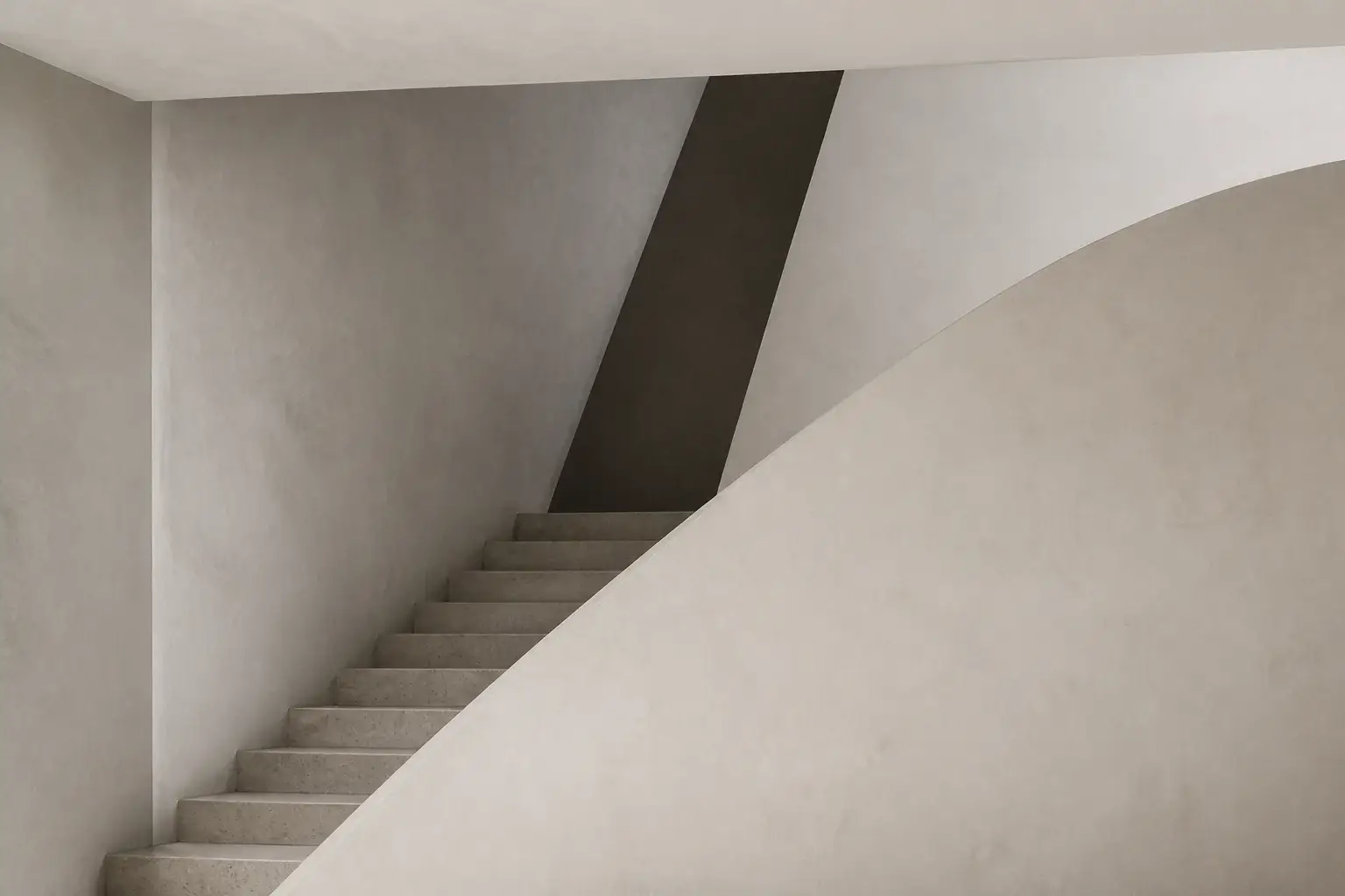 Sculptural limestone staircase rising behind a curved plaster wall